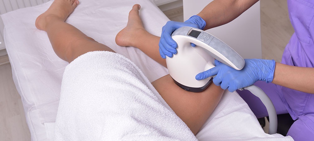 VelaShape III handpiece guided across a client's thigh during a cellulite and skin-tightening session at Sculpted Body Curves